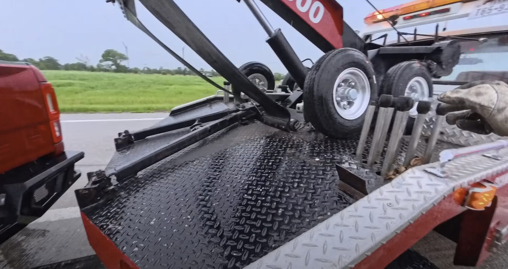 Professional tow truck operator loading vehicle using proper flatbed towing techniques