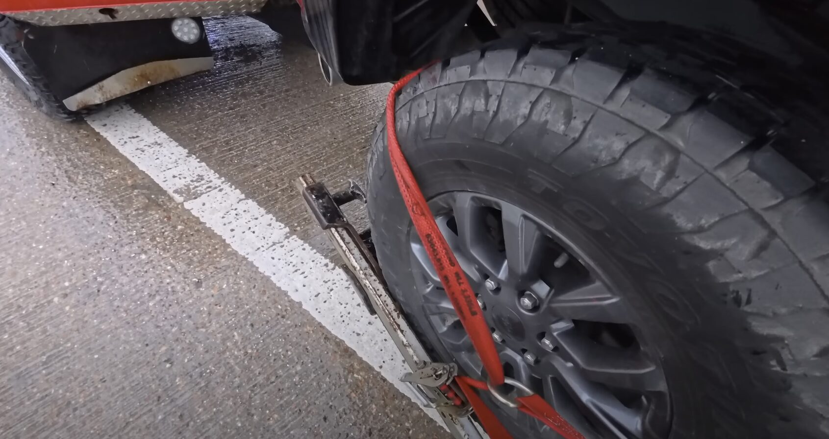 Vehicle being secured with professional towing equipment and safety straps