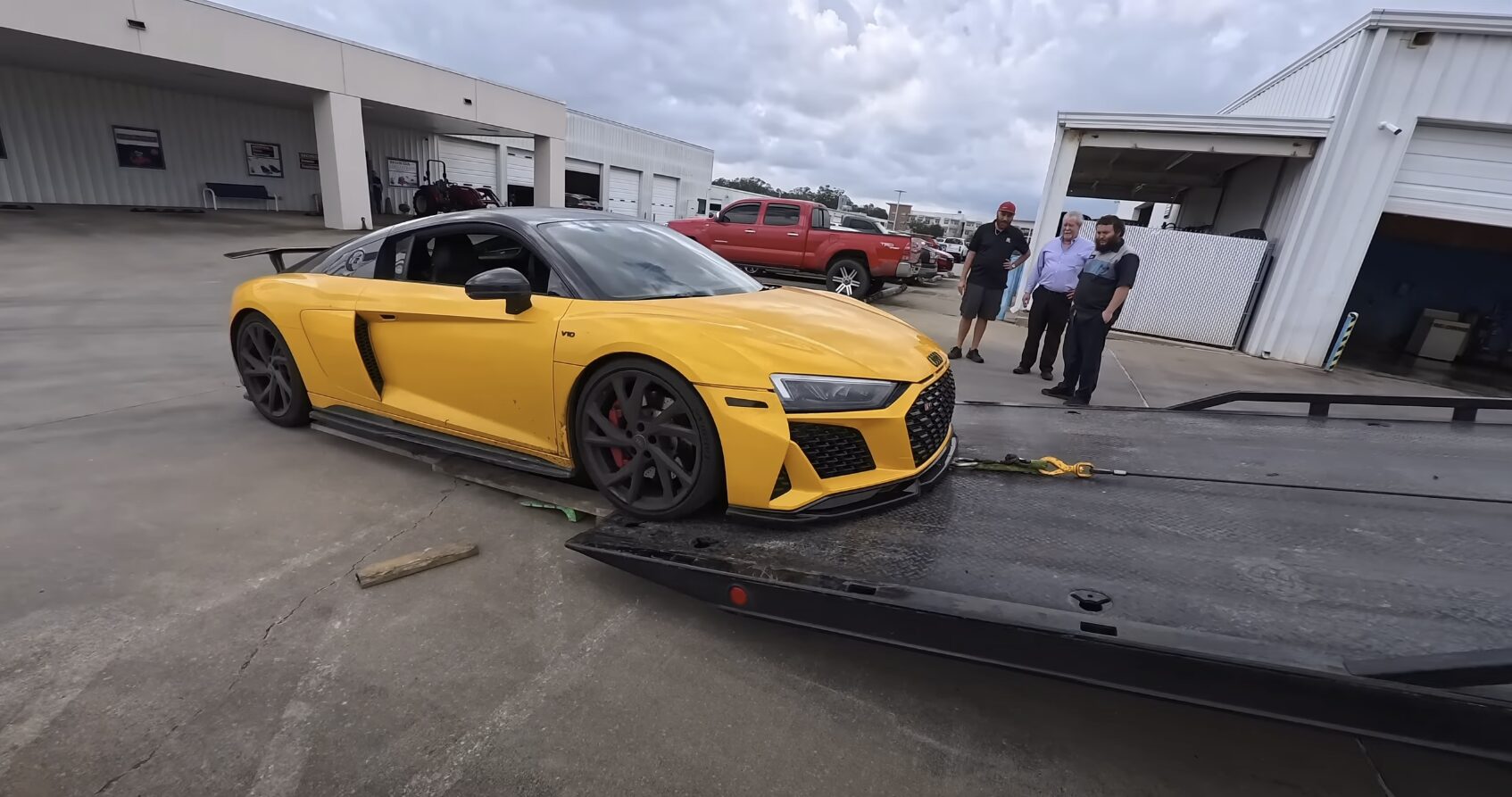 Luxury yellow sports car being loaded onto professional flatbed tow truck